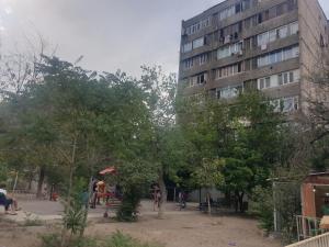 埃里温Sunny Apartment close to Erebuni mall的一座高大的建筑,人们坐在公园周围