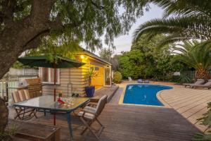 帕拉帕拉乌姆海滩Kapiti Getaway - Paraparaumu Beach Rental的一个带桌椅的庭院和一个游泳池