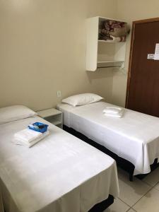 瓜拉图巴Stela Maris的配有白色床单的酒店客房内的两张床