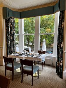 哈罗盖特Ascot House的一间带桌子和大窗户的用餐室