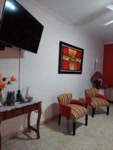 布兰卡港Departamento Luiggi con cochera的客厅配有电视、2把椅子和1张桌子