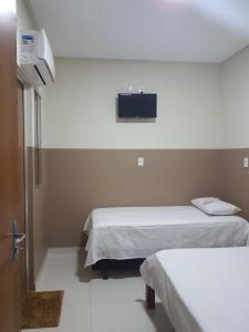 邦热苏斯-达拉帕Center Prime Hotel的客房设有两张床和一台墙上的电视。
