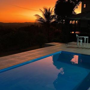 圣湖镇Casa da Vista - LAGOA SANTA的蓝色的游泳池,背景是日落