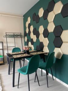 德布勒森Bella Apartman Debrecen的一间带桌子和绿色椅子的用餐室