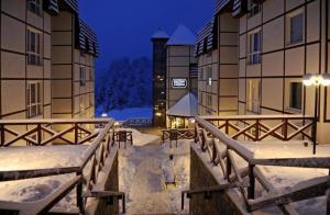 科帕奥尼克KATARINA - Lux two bedroom apartment in ski resort Kopaonik的夜间两栋建筑之间有雪覆盖的走道