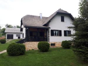 波利亚纳克Holiday house with a parking space Poljanak, Plitvice - 15340的白色的房子,有黑窗和院子