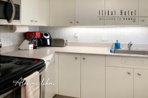 檀香山New Aloha Ilikai 1free Parking的厨房配有白色橱柜、水槽和炉灶。