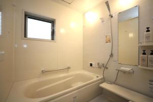 京都一棟貸切り宿 GuestHouse 嵯峨嵐山的白色的浴室设有浴缸和窗户。