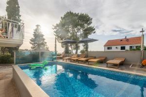 苏提万Family friendly apartments with a swimming pool Sutivan, Brac - 15665的房屋旁的带桌椅的游泳池