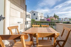 苏提万Family friendly apartments with a swimming pool Sutivan, Brac - 15665的阳台上的木桌和椅子