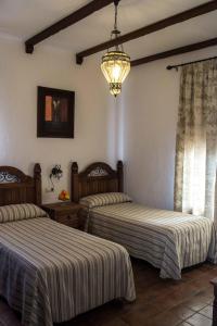 HinojalesCasa Rural Sierra Tórtola 2的一间卧室配有两张床和吊灯。