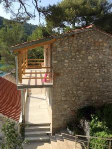 博格莫耶Secluded fisherman's cottage Cove Kozja, Hvar - 16058的石头建筑顶部的木甲板上设有长凳