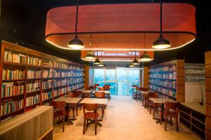 拉杰沙希Royal Raj Hotel的图书馆配有桌椅和书架