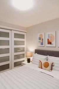 渥太华Modern, Luxurious Apartment near Downtown Ottawa的白色的卧室配有一张白色的大床和一盏灯
