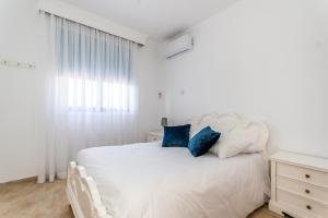 拉纳卡Reel Paradise Villa, Cyprus的白色卧室配有白色床和蓝色枕头