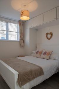 马根波思Hegarty's cottage at Trevarrian Lodge的白色卧室设有一张大床和一面心镜子