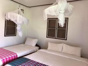 Ban OKonglor Eco-Lodge Guesthouse and Restaurant的带窗帘的窗户的客房内的两张床
