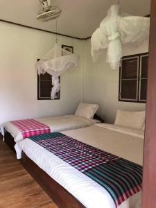 Ban OKonglor Eco-Lodge Guesthouse and Restaurant的白色墙壁客房的两张床