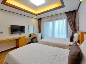 西归浦市Fellisia Hotel的酒店客房设有两张床和一台平面电视。