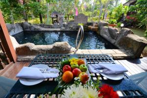 珍拉丁LaVilla By Holiday Villa Cherating的池塘旁的野餐桌上放水果