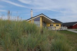 格罗森布罗德Resort 2 Ferienhaus Typ D 122的海滩上一座黄色房子,上面有高大的草