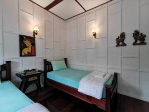 曼谷TAVEE Guesthouse的小房间设有两张床和一张桌子