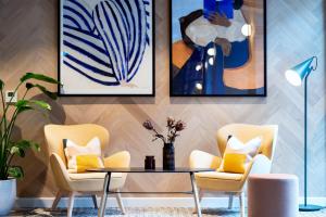 都柏林Staycity Aparthotels Dublin City Centre的客厅配有椅子、桌子和绘画作品