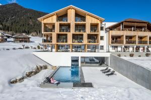 瓦莱迪卡谢斯蒂罗尔酒店的一座在雪中设有游泳池的建筑