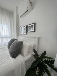 哥打巴鲁The Penthouse TROIKA KOTA BHARU的一间卧室配有白色床单和植物