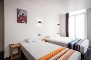 佩皮尼昂Hôtel PB - Paris-Barcelone的酒店客房设有两张床和窗户。
