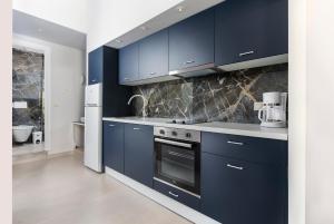 干尼亚TheJoy Residence Apartments的厨房配有海军蓝的橱柜和炉灶。