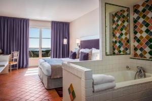 邦多勒Le Fregate Provence的酒店客房配有一张床和浴缸。