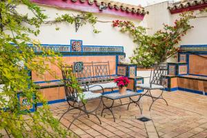 塞维利亚CASA17 Santacruz Suites的庭院设有椅子、长凳和鲜花