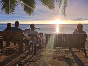AmuriSunny Beach Bungalows - Aitutaki的一群坐在长凳上观看日落的人
