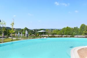 明乔河畔的瓦雷奇奥Agricampeggio Corte Tonolli的一个带椅子和遮阳伞的大型蓝色游泳池