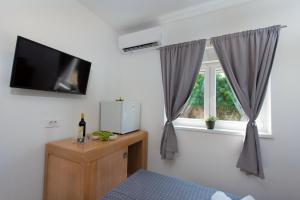 PotpićanHotel Potpican的客房设有电视和带窗帘的窗户。