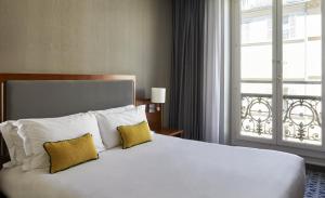 巴黎Crowne Plaza Paris République, an IHG Hotel的一间卧室配有一张大床、两个枕头和窗户
