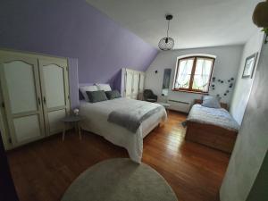 奥贝奈Gite des écureuils的紫色卧室设有两张床和一扇窗户