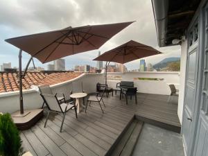 波哥大REPUBLICANA CASA HOSTAL - HABITACION 5 TAIRONA的屋顶上带桌椅和遮阳伞的天井