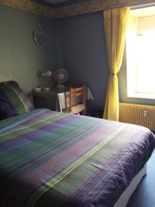 南希Chambres d'hôtes Olry的一间卧室配有一张带条纹毯子的床和窗户