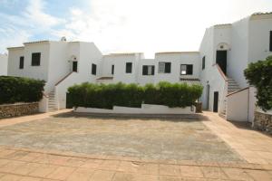 蓬塔格罗萨Cove Noves - Relax en Menorca, Ideal para familias的一座白色的大建筑,前面有一个庭院