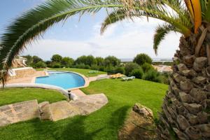 蓬塔格罗萨Cove Noves - Relax en Menorca, Ideal para familias的棕榈树庭院中的游泳池