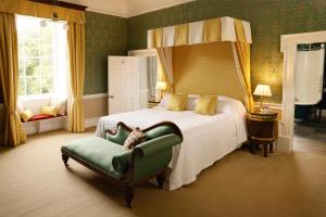 Riverstown库珀斯希尔酒店的一间卧室配有一张床和一把绿色椅子