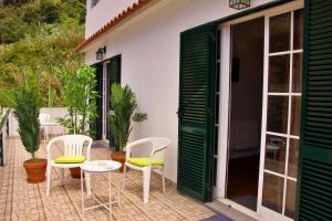 丰沙尔Ivone Madeira Guest House的庭院配有白色的椅子和桌子