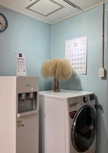 木浦市Jo Eun Jip Guesthouse的洗衣房配有洗衣机和时钟