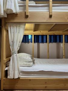 木浦市Jo Eun Jip Guesthouse的配有白色床单和窗帘的双层床