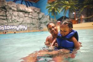 桑达斯基Castaway Bay by Cedar Point Resorts的游泳池里的男人和小女孩