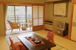 箱根桐谷箱根庄酒店的一间带桌子和电视的客厅以及一间带阳台的客房。