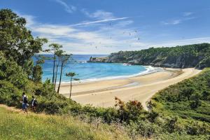 卢阿尔卡Room in Lodge - Pension Oria Luarca Asturias的两个人沿着海边散步