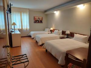 利马Lima Wasi Hotel Miraflores的酒店客房设有三张床和窗户。